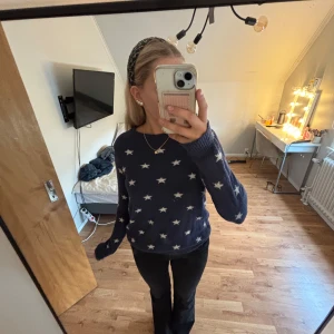 Mörkblå stickad tröja med stjärnor L.O.G.G. - Mysig mörkblå stickad tröja från L.O.G.G. med vita stjärnor över hela. Tröjan har rund halsringning, långa ärmar och ribbade muddar. Perfekt för dig som gillar en chill och snygg look med lite extra detaljer.