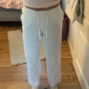 Vita linnebyxor från Gina Tricot - Säljer ett par vita linnebyxor från Gina Tricot i storlek 146/152. Byxorna har rak passform, snörning runt midjan. Perfekta för varma dagar och riktigt sköna att ha på sig.