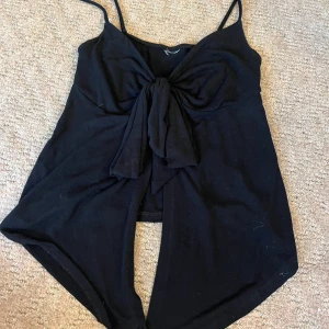 Svart linnetopp från Gina tricot  - Snygg och trendig svart linnetopp med smala axelband och stor knytning framtill. Från Gina tricot och använd 1 gång🤍