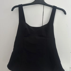 Snygg svart topp -  Säljer denna snygga svarta toppen från Zara. Den är super söt och har en rosett i ryggen. Den är i helt nytt skick. Prislappen finns kvar. Hör av er vid frågor om pris eller annat!🥰nypris 329