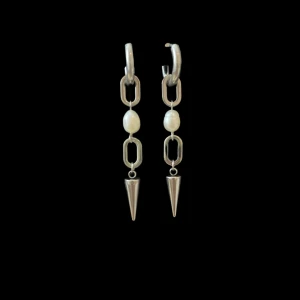 Silverörhängen med kedja och pärlor - Snygga örhängen i silverfärg med kedjelänkar, vita pärlor och spetsiga konformade hängen. De har en cool och edgy design som sticker ut och passar perfekt för dig som gillar statement-smycken.