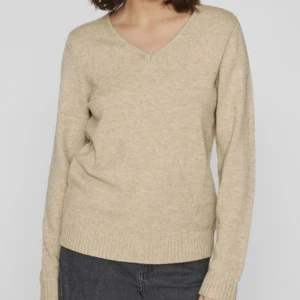 Beige stickad v-ringad tröja - GARDEROBSRENSNING! En stilren beige stickad tröja med v-ringning och långa ärmar. Tröjan har ribbade muddar vid ärmslut och nederkant, vilket ger en snygg och enkel look. Perfekt att matcha med jeans eller kjol för en chill vibe. 