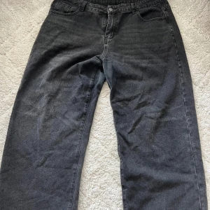 Svarta raka jeans med loose fit - Säljer ett par svarta jeans med rak passform och loose fit. Jeansen har klassisk femficksdesign, bälteshällor och knappgylf. Perfekta för dig som gillar en avslappnad och stilren look.