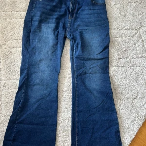 Blå bootcut jeans med raka ben - Snygga blå jeans med bootcut-modell och raka ben. Klassisk femficksdesign och normal passform. Jeansen har en djupblå färg och är tillverkade i ett slitstarkt denimtyg. Perfekta för dig som gillar en tidlös och avslappnad stil.