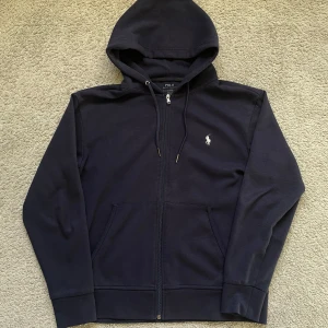 Polo Ralph Lauren zip hoodie - Tja, säljer en tvär fet polo Ralph lauren zip hoodie i färgen mörkblå storlek S, tröjan har inga defekter och är i väldigt bra skick, säljer pågrund av att jag tröttnat på den, perfekt för sena sommarkvällar🌄(modellen är 178 cm lång), skriv vid minsta lilla och pris går att diskutera vid snabb affär🥂🍾