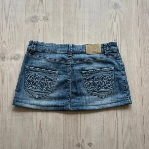 Ljusblå lågmidjad jeanskjol  - Blå lågmidjad jeanskjol från Flash jeans i storlek 40, passar S och M. Fint skick. Tvärs över midjan är det ca 41 cm och den är ca 29 cm lång (längs med sidan). Använd gärna köp nu!
