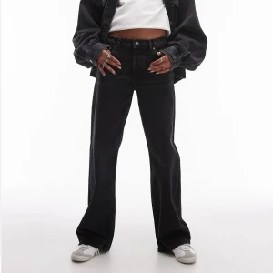 Jeans Topshop ’Ember’  - Oanvända jeans från Topshop i tvättad svart med låg midja och breda ben. Jeansen har femficksdesign och knappar framtill och alla lappar sitter kvar. 