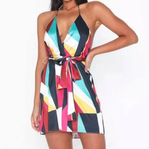 Färgglad kort halterneck klänning - Snygg kort klänning med färgstarkt randigt mönster i blått, rött, gult, vitt och svart. Djup v-ringning, öppen rygg och knyt i midjan. Klänningen är ärmlös och har tunna axelband som knyts i nacken. Perfekt för sommarens alla tillfällen