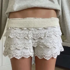 Beige spetsshorts med volanger - Superfina beige virkade shorts med flera lager volanger. De har en elastisk midja och är perfekta för varma dagar. Postar inom 24 timmar!
