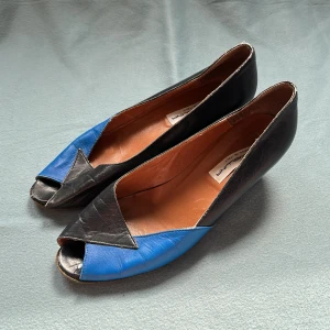 Vintage peep-toe skor  - Äkta läder, storlek 38.5. Svart med blå detalj framtill och på klacken. Från 60/70-talet – ärvt från min farmor 💙 Jätteunik retrostil! Lite slitage i kanten och undersulan men inget som stör funktionen. Säljes pga de inte passar mig!
