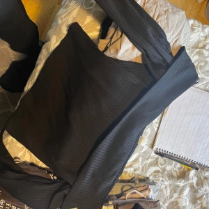 Svart ribbad offshoulder topp M - Säljer en svart ribbad offshoulder topp i storlek M. Toppen har långa ärmar och är figurnära med snygg stretch. 