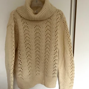 Beige stickad polotröja med hålmönster - Supermysig beige stickad polotröja från H&M med snyggt hålmönster framtill. Tröjan har en bred, ribbad polokrage och långa ärmar. Perfekt för lager-på-lager och chill höst- och vinterstil.
