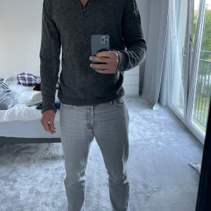 Mörkgrå stickad tröja Selected Homme - Mörkgrå stickad tröja från Selected Homme med ribbade muddar och krage. Tröjan har en half zip-dragkedja vid halsen och är långärmad. Perfekt för lager-på-lager och chill höst- och vinterstil.