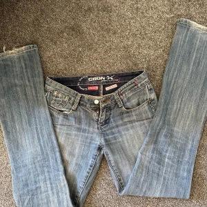 Ljusblå jeans från Cron-X med brodyr - Ljusblå jeans från Cron-X med snygg slitning och broderade detaljer på bakfickorna. Klassisk femficksmodell, dragkedja och knapp i midjan. Råa, fransiga benslut ger en avslappnad vibe. Perfekta för dig som gillar en casual och trendig look. Dragkedjan är sönder men det går att laga eller byta ut💗