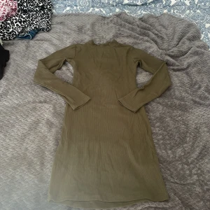 Olivgrön ribbad klänning Bik Bok XS - Säljer en olivgrön ribbad klänning från Bik Bok i storlek XS. Klänningen har lång ärm, hög hals och är figurnära med stretchigt material. Perfekt för dig som gillar enkel men snygg stil. Har en fläck men som går bort i tvätten❤️