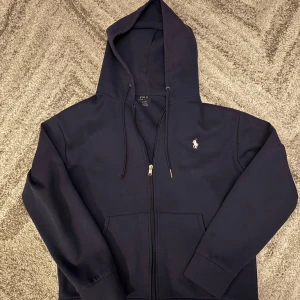 Polo zip hoodie - Tröjan i bra skick. Inga fläckar eller hål. Inga problem med dragkedjan. Ena ensam av snöret är sönder som man kan se på bild.