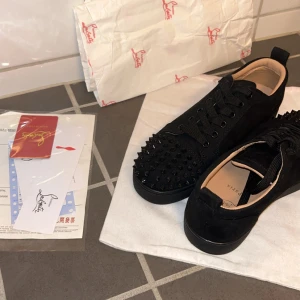 Christian Louboutin - KVITTO FINNS!!!                                                   PRISET ÄR INTE HUGGET I STEN Christian Louboutin Louis Junior Spikes – Storlek 40  Säljer ett par snygga och lyxiga sneakers från Christian Louboutin i storlek 40 Modellen heter Louis Junior Spikes och har svarta nitar framtill som ger ett unikt och stilrent utseende. Skorna är bara använda 2 gånger och är i mycket fint skick. Allt original påse, papper och kvitto finns kvar.Nypris ligger på över 9000 kr – perfekt chans att fynda!