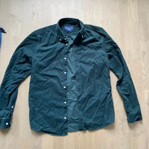 Mörkgrön manchesterskjorta - Snygg mörkgrön skjorta från Brooksfield i mjuk manchester. Klassisk krage med knappar och vita knappar längs hela framsidan. Perfekt för dig som gillar en stilren och avslappnad look. Långärmad modell som passar året runt.