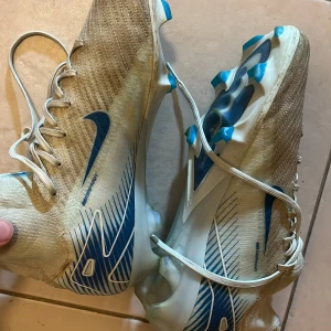 Nike fotbollsskor i vitt och blått - Snygga Nike fotbollsskor med högt skaft i vitt och blått. Priser är hugget i sten.