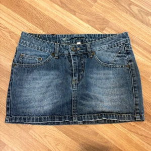 Klassisk jeanskjol i blå denim - Snygg kort jeanskjol i blå denim med klassisk femficksdesign, bälteshällor och knappstängning framtill. Perfekt basic-plagg med slitna detaljer och raka linjer. Passar till allt och är superenkel att styla med sneakers eller boots. Använd fåtal gånger, skriv för bilder eller frågor. Alltid öppen för att diskutera pris.🤗💕