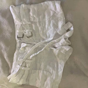 Vita linneshorts med bältdetaljer ICHI - Snygga vita shorts från ICHI i linne med låg midja. De är i ett jätte fint skick (skulle endast behöva strykas). Inga defekter eller annat förekommer. Storlek 36/38. Det står M, men skulle säga mer S/M🩷