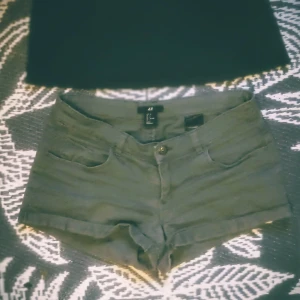 Militärgröna bekväma shorts - Snygga gröna shorts från H&M i klassisk femficksmodell. De har låg midja, uppvikta benslut och stängs med knapp och dragkedja. Perfekta för varma dagar och enkla att matcha med allt. Materialet är mjukt och skönt, troligtvis bomull med lite stretch.