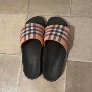 Burberry sandaler med klassiskt rutmönster - Tjenare, säljer ett par Burberry Tofflor i storlek 42. Tofflorna är i super bra skick och har du frågor är de bara att höra av dig✌️