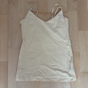 Gul linnetopp från 157, stl S - Supersöt gul linnetopp från 157 med smala axelband och enkel, rak passform. Tillverkad i mjuk bomull med lite stretch för extra komfort. Perfekt att matcha med jeans eller kjol för en chill look.