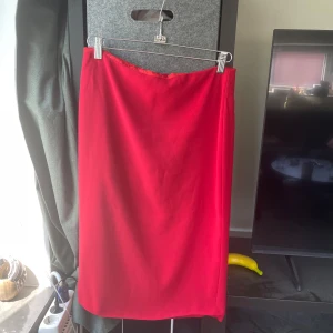 Röd långkjol från My Time - Snygg röd långkjol från My Time med klassisk rak passform. Kjolen har en enkel design med dragkedja bak och är perfekt för dig som gillar stilrena plagg. Materialet känns mjukt och följsamt, vilket gör den bekväm att bära hela dagen.