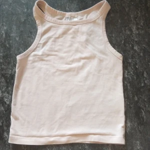 Ljusbeige linnetopp från H&M Divided XS - Enkel och stilren ljusbeige linnetopp från H&M Divided i storlek XS. Modellen är ärmlös med klassisk rund halsringning och rak passform. Perfekt att matcha med jeans eller kjol för en clean look.