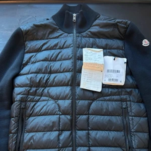 Moncler Cardigan - Svart Moncler Tricot Down Cardigan | Nypris: 10 000kr | Size: L (sitter som M) | Skick: 9,5/10 | Du får med tags och kvitto! | Äktenhetsbevis från GarmsMarket | Hör av dig vid minsta fråga eller fundering//