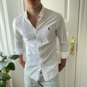 Slim fit vit Ralph Laruren skjorta - Minimala svett fläckar under armarna men märks verkligen inte. Annars är det inga defekter. Modellen är 180,75 kg och bär Slim fit S. Kom med frågor!