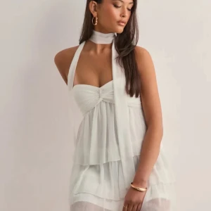 Vit kortklänning med scarfdetalj - Supersöt vit kortklänning med lager på lager-känsla och scarf runt halsen. Klänningen är från Nelly och jag har bara använt den 1 gång säljer för att den inte kommer till användning 