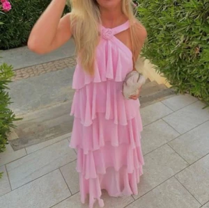 Vero Moda VMFELICA rosa volangklänning  - Vero Moda VMFELICA. Superfin långklänning i ljusrosa med flera lager volanger och halterneck med rosettdetalj framtill. Klänningen har öppen rygg och breda axelband. Endast använd en gång. INTE mina bilder men kan absolut fixa bara skriv ett PM!