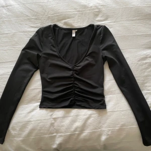 Svart långärmad topp från Nelly XS - Säljer denna svarta långärmade toppen från Nelly i storlek XS. Toppen har v-ringning och rynkdetalj framtill. Den är i mycket bra skick.