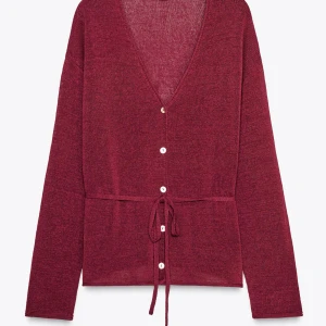 Vinröd kofta med knyt och knappar - Snygg vinröd kofta med v-ringning, knappar framtill och knytband i midjan. Långärmad och i mjukt stickat material som ger en chill och stilren vibe. Perfekt att slänga över en topp eller klänning för en extra touch.