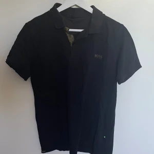 Hugo Boss Piké - Säljer denna snygga Hugo Boss pikén i storlek L, passar mig som brukar bära S-M så något liten i storleken. Bra skick utöver den översta knappen som lossnat men syns ej så länge man ej vill stänga kragen helt! Hör gärna av dig vid frågor eller prisförslag!