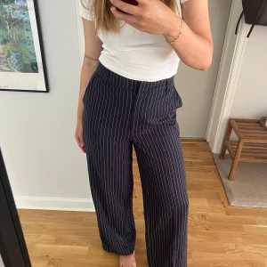 Randiga vida byxor från BikBok - Snygga mörkblå byxor med vita ränder från BikBok. De har hög midja och ett wide fit som ger en chill och trendig look. Perfekta att styla med en enkel topp eller hoodie. 