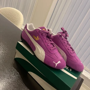 Puma sneakers - Snygga lila Puma sneakers i mocka med vita detaljer och svart sula. Klassisk design med snörning, guldfärgad Puma-logga på sidan och vit logga på tån. Storlek 39 (har i 38,5 och 40,5 också). 1300 sek på zalando