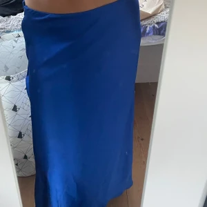  långkjol Lindex - fin stark blå färg. Kjolen har en slät, glansig yta och stängs med dragkedja i sidan. Perfekt för dig som gillar en enkel men snygg look. Materialet känns lätt och följsamt mot kroppen.
