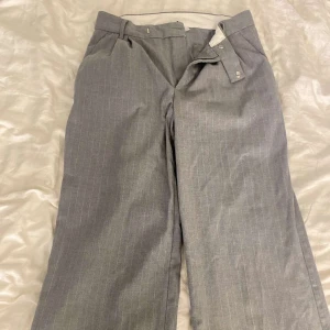 Grå kostymbyxor - Snygga grå kostymbyxor från divided, HM, med smala vita ränder. Byxorna har raka ben. 