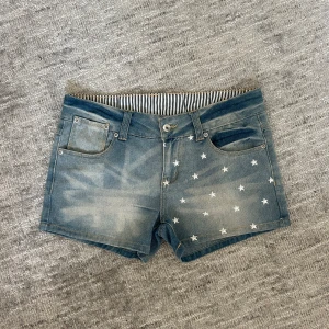 Lågmidjade jeansshorts med stjärnor - Snygga lågmidjade jeansshorts från Smiling med slitna detaljer och vita stjärnor på framsidan. Så snygga nu i sommar!! Midjemåttet rak över är 39cm, hör av er vid frågor!💕 (pris kan diskuteras)