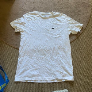 Vit t-shirt - Vit t-shirt från Lee i bomull, klassisk modell med korta ärmar och rund hals. Bröstficka med liten Lee-logga ger en clean och stilren vibe. Perfekt basic-plagg att ha i garderoben!🙌🏻