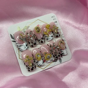 RoyalWild(M);Medium Square - Set med gelé press on-naglar i rosa bas med zebramönster och leoparddetaljer. Utsmyckade med stora 3D-dekorationer i guld och silver, som kors, rosetter, stenar och blommor. Naglarna är medium långa och fyrkantiga, perfekta för dig som vill sticka ut. I storlek M: 16 mm, 12 mm, 12,5 mm, 11,5 mm, 10 mm