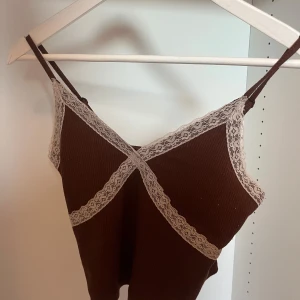 Brun ribbad linnetopp med spets - Supersöt brun ribbad linnetopp med tunna axelband och ljus spetsdetalj längs urringningen och framtill. 