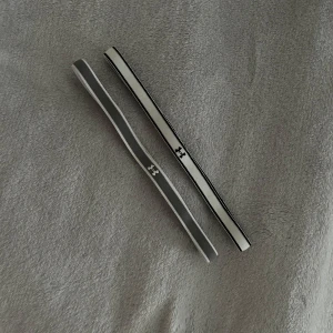 Under Armour hårband  - Två smala hårband från Under Armour. Båda har Under Armour-loggan framtill och är tillverkade i elastiskt syntetmaterial som håller håret på plats under träning.