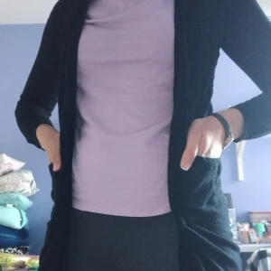 Svart tunn lång kofta - Enkel och stilren lång svart kofta från Lager157 i storlek XS. Koftan har lång ärm, öppen framtill och två fickor. Perfekt att slänga över en t-shirt eller topp för en chill look. Materialet är mjukt och känns skönt mot huden.