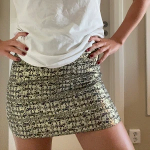 Mönstrad kortkjol i beige/guld och svart - Säljer en snygg kortkjol med beige botten och svart mönster. Kjolen har en rak och tight passform som sitter högt i midjan