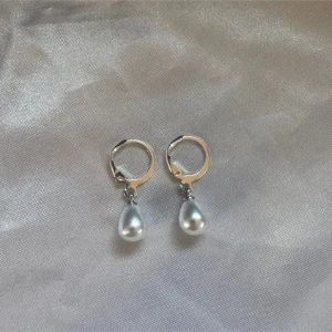 Silverörhängen med droppformade pärlor - Stilrena örhängen i silverfärg med droppformade pärlor som hänger från små ringar. Perfekta för dig som gillar en klassisk och elegant look. Pärlorna har en fin glans och örhängena är lätta att bära hela dagen.