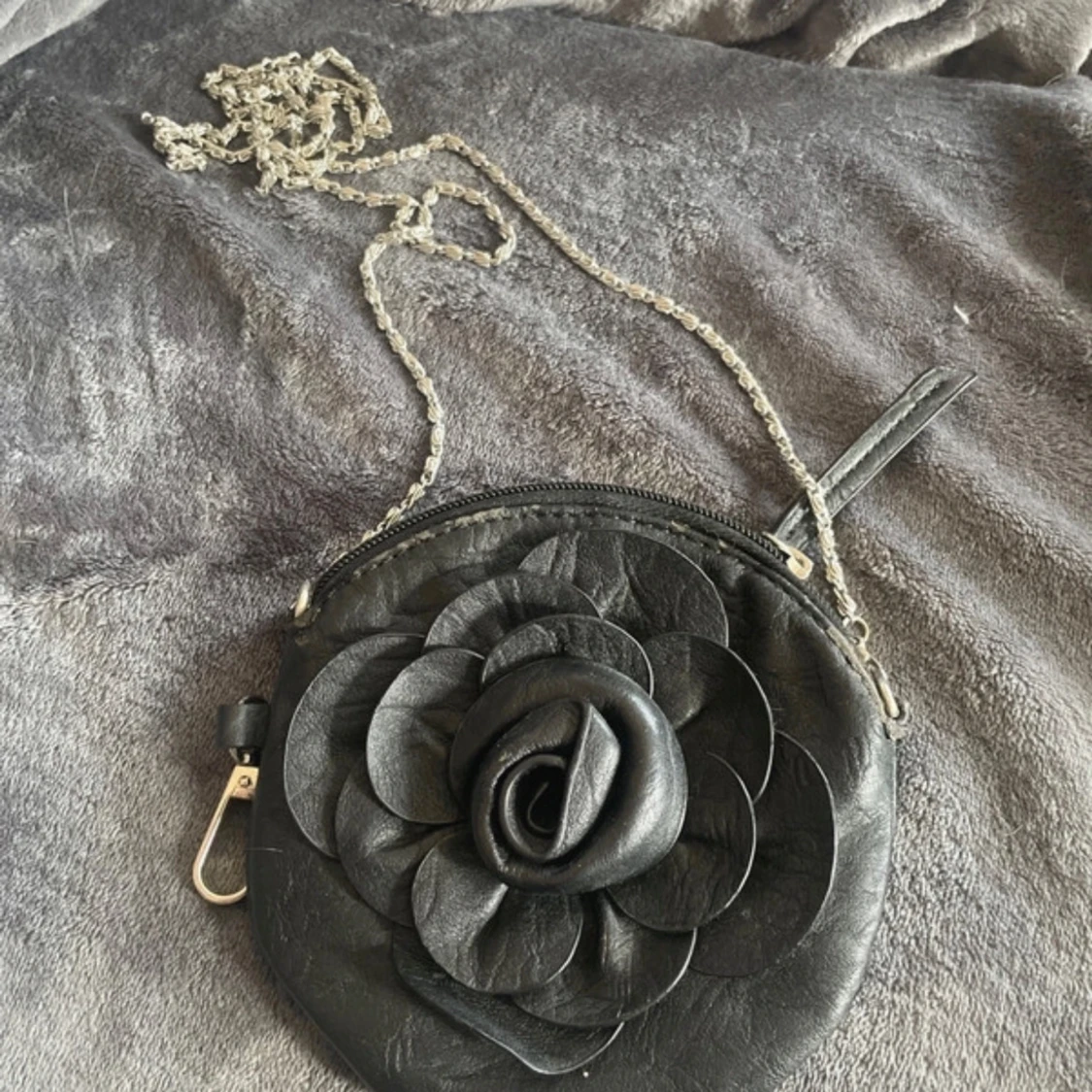 Svart rund axelväska med blomdetalj